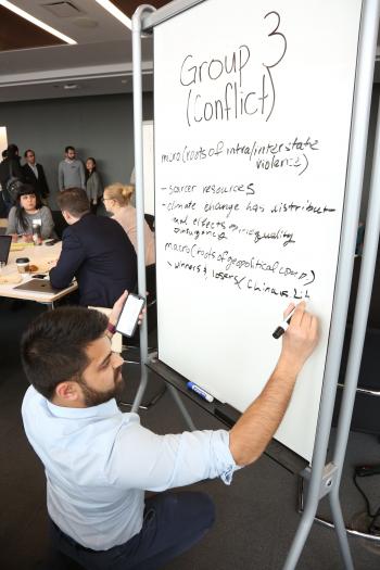 A Harris Public Policy student writes on a whiteboard.